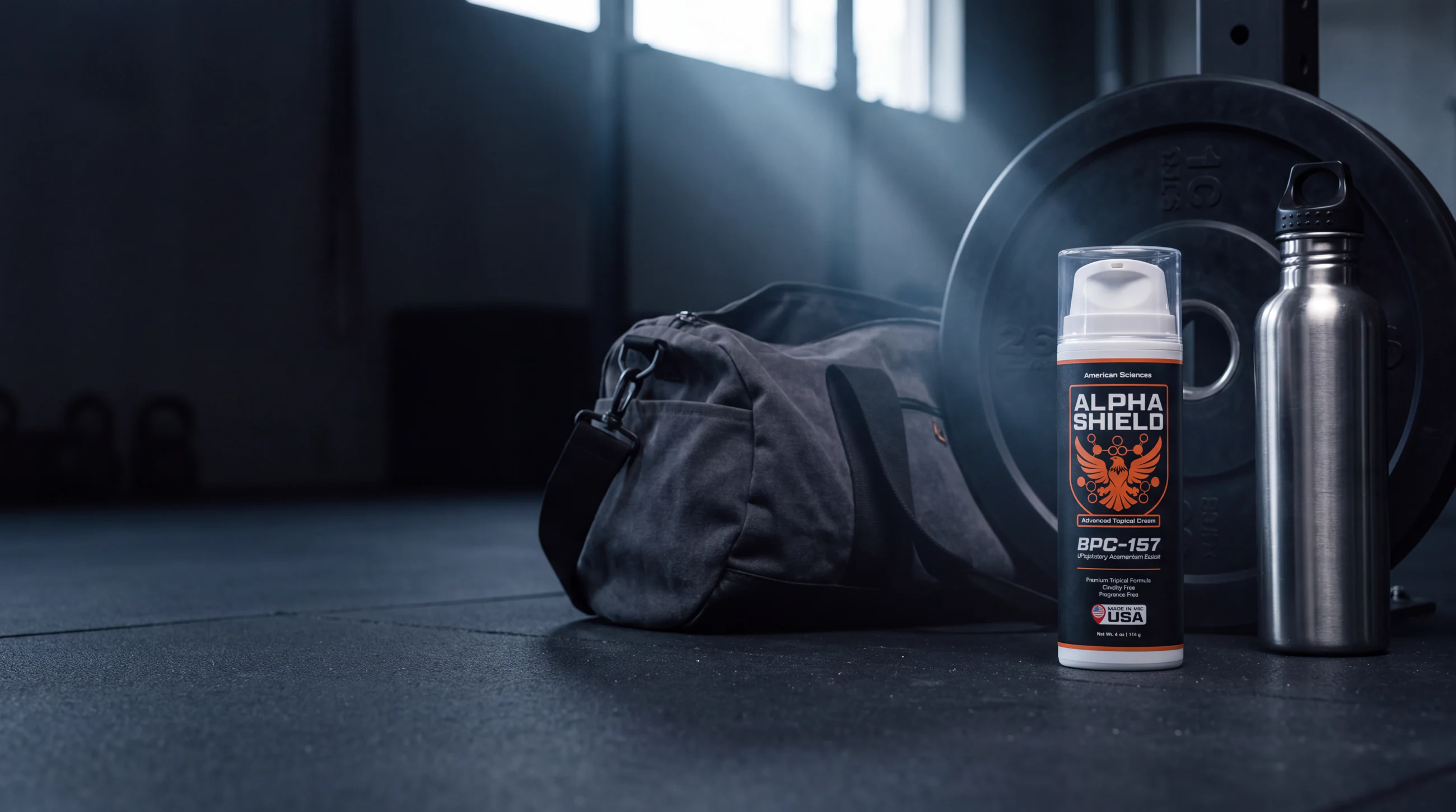 Labelled Alpha Shield bottle beside an open gym bag and a weight plate